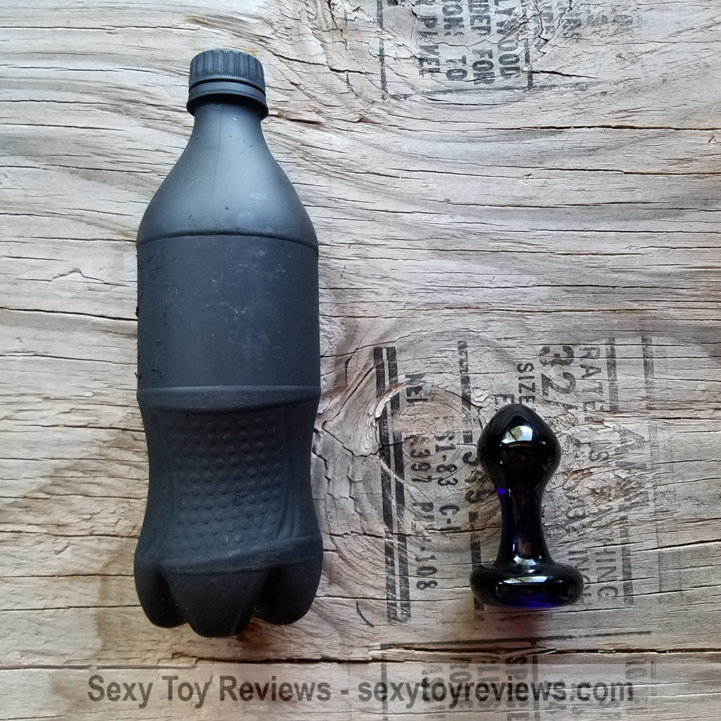Princess butt plug next to cola bottle for size comparison