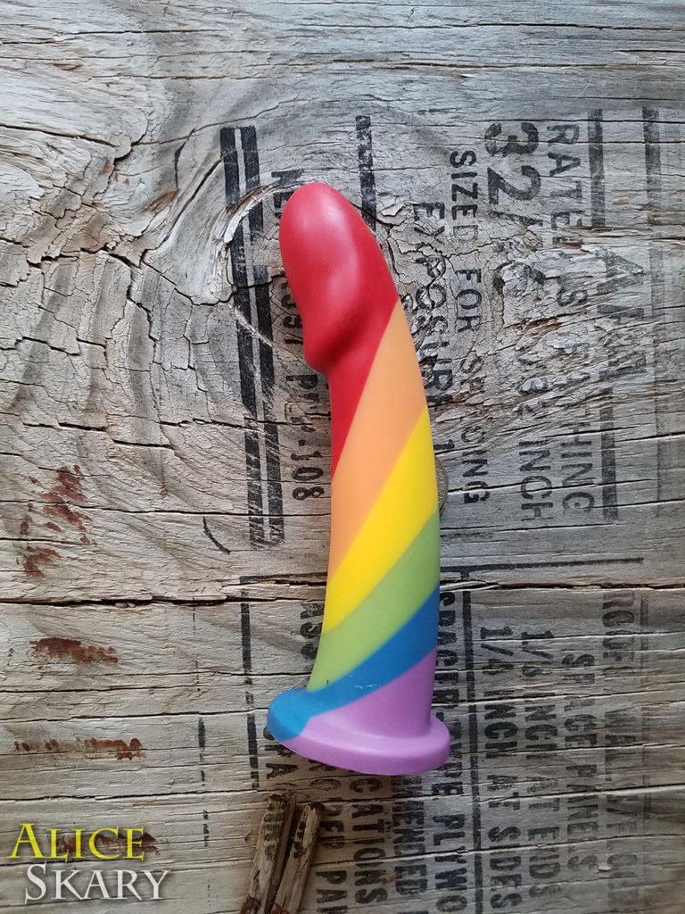 A colorful rainbow dildo on a wood background