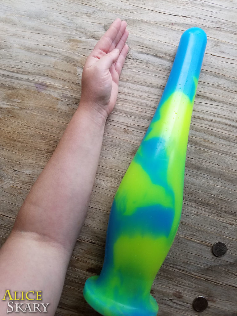 A huge silicone sex toy pictured next to a forearm